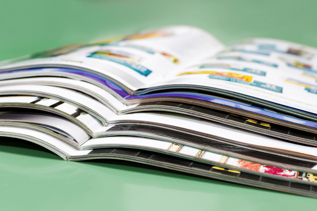 Brochure promozionali impilate con pagine lucide aperte su sfondo verde per catalogo prodotto e marketing aziendale